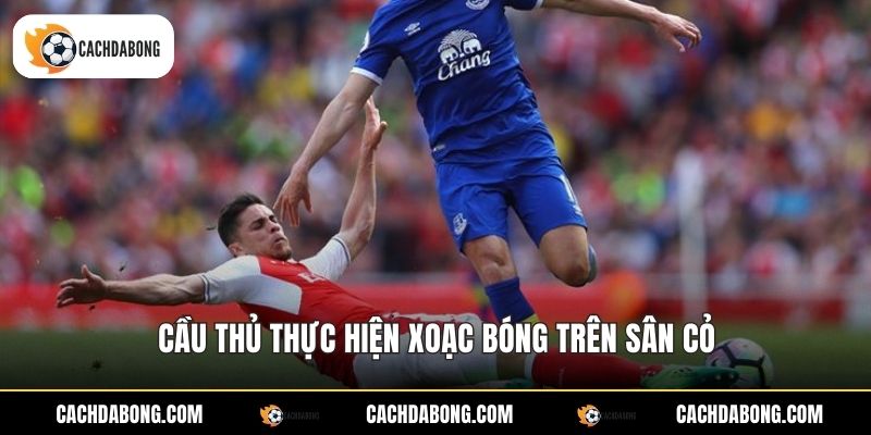 Cầu thủ thực hiện xoạc bóng trên sân cỏ